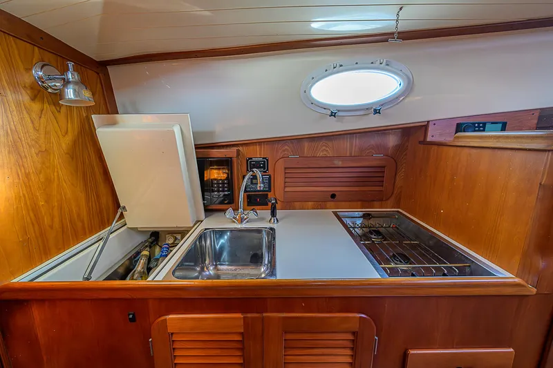 Lucky Town Yacht Photos Pics 2000 Hinckley Picnic Boat Classic interior galley with sink, stove, and wooden cabinetry.