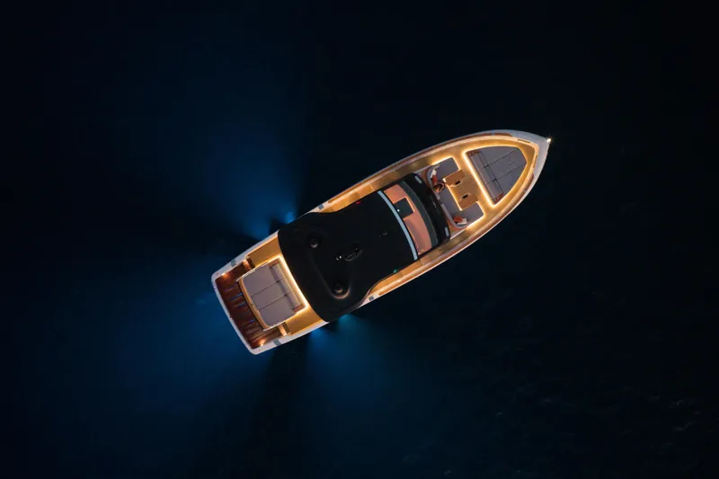  Yacht Photos Pics Aerial view of 2025 Invictus TT550 yacht illuminated at night on water.