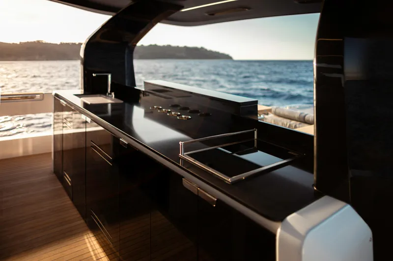  Yacht Photos Pics Luxurious Invictus TT550 yacht kitchen with sleek black countertops, overlooking serene ocean view.