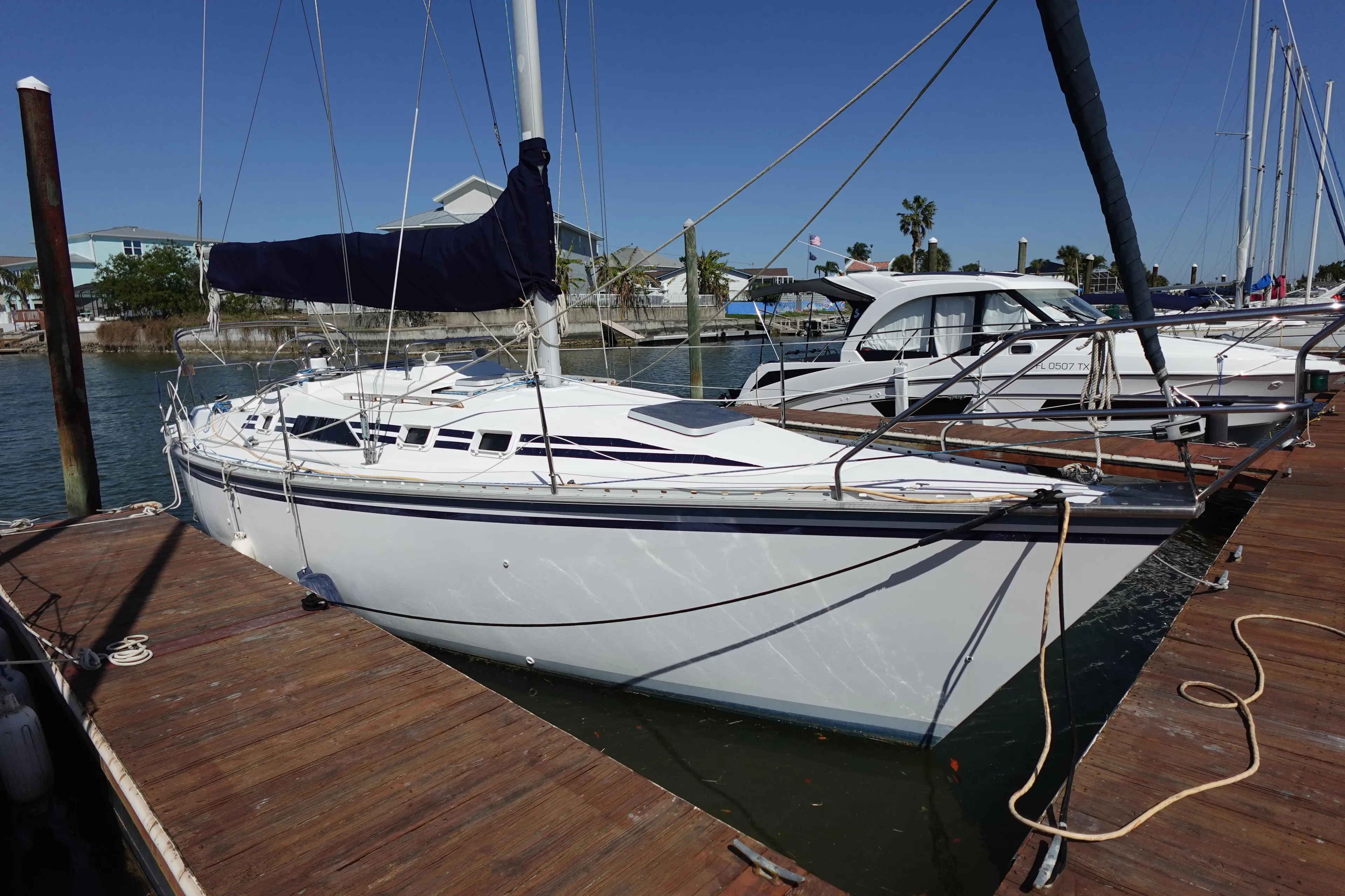 1987 Hunter 310 sailboat docked at marina under clear blue sky.
