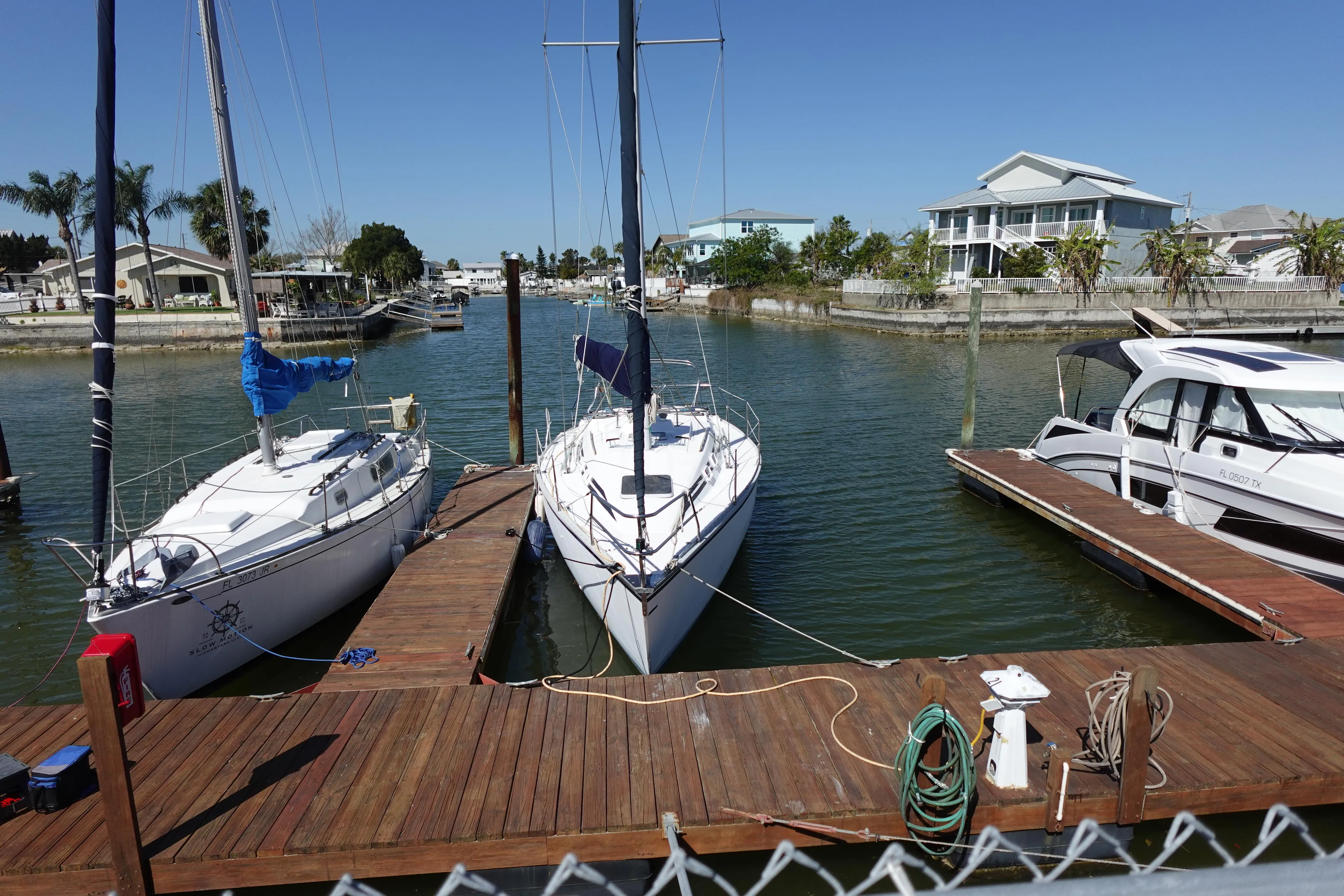 1987 Hunter 310 sailboats docked at a marina with waterfront homes in the background.