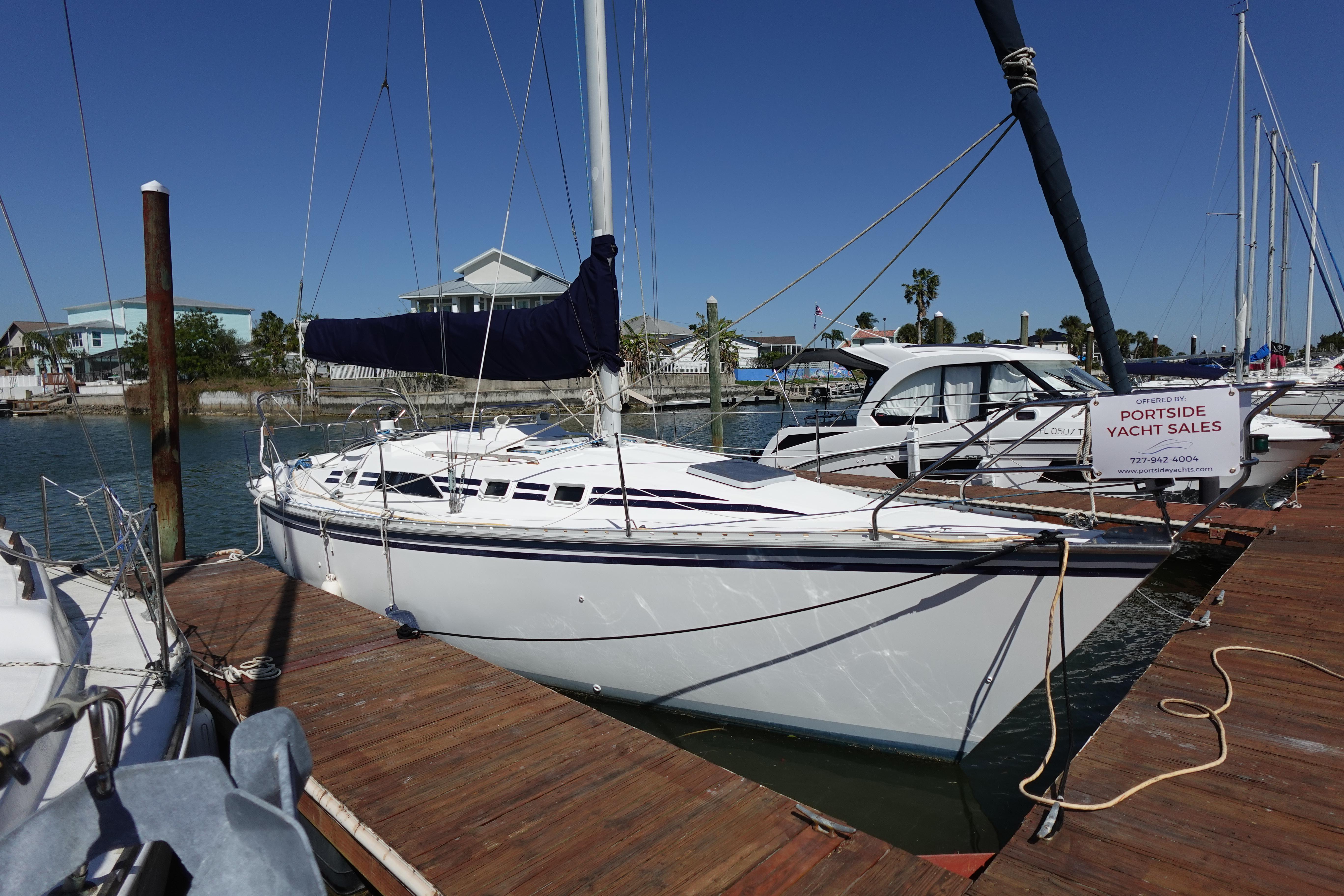 1987 Hunter 310 sailboat docked at marina under clear blue sky.