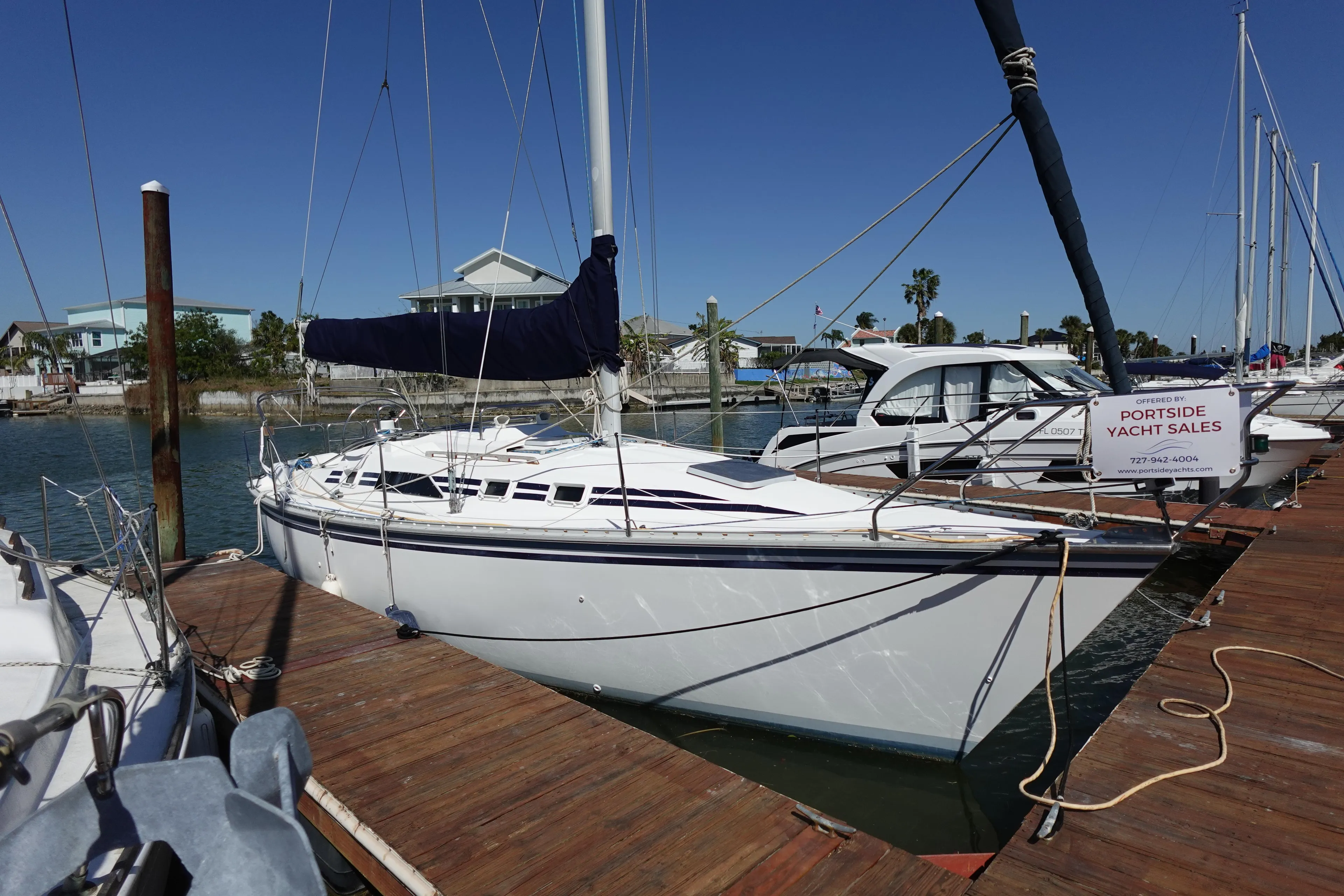 1987 Hunter 310 sailboat docked at marina under clear blue sky.
