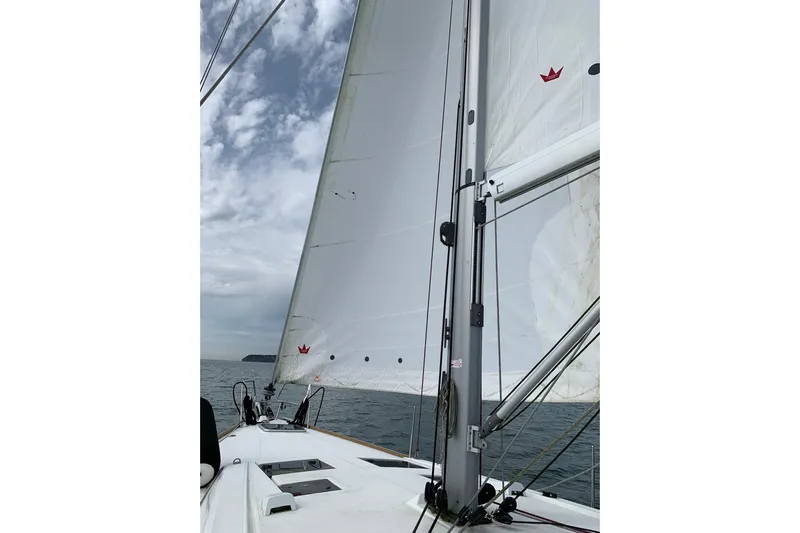 V-1 Yacht Photos Pics Sailing on a 2018 Beneteau Oceanis 45 with white sails against a cloudy sky.