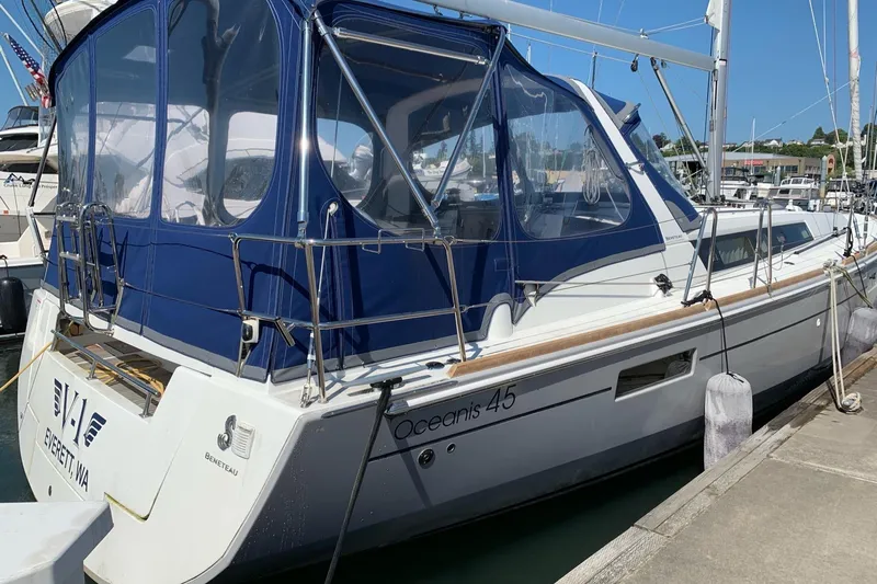 V-1 Yacht Photos Pics 2018 Beneteau Oceanis 45 sailboat docked with blue canopy in marina.