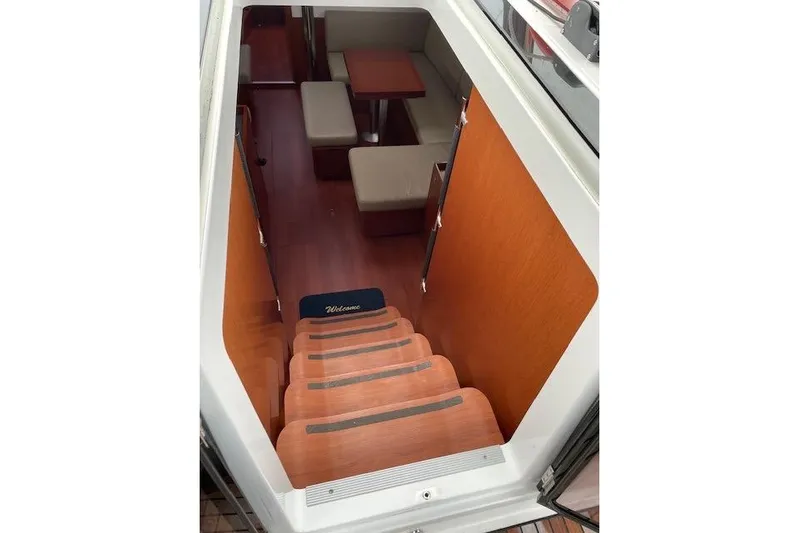 V-1 Yacht Photos Pics Interior view of 2018 Beneteau Oceanis 45 yacht, featuring wooden stairs and cozy seating area.