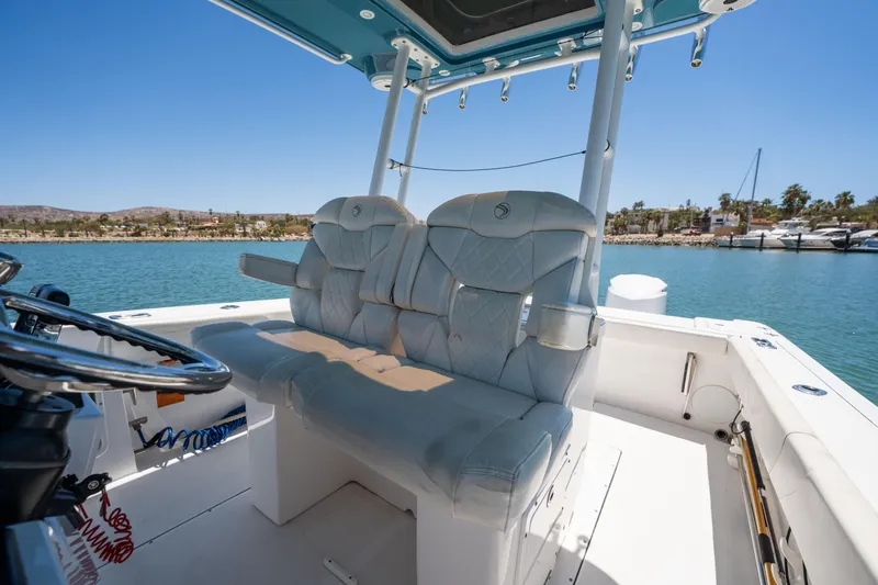 Carnal Yacht Photos Pics 2020 Edgewater 320CC boat interior with cushioned seating, steering wheel, and ocean view.