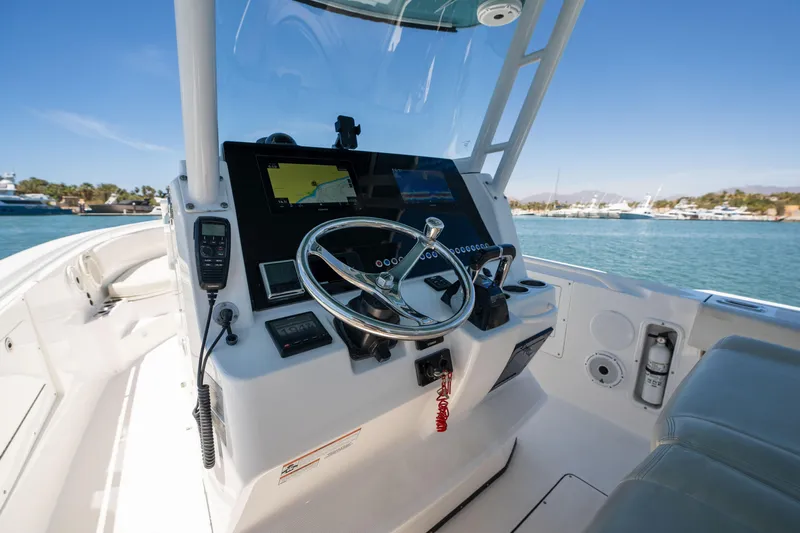 Carnal Yacht Photos Pics Edgewater 320CC 2020 boat cockpit with steering wheel and navigation equipment, docked by the water.