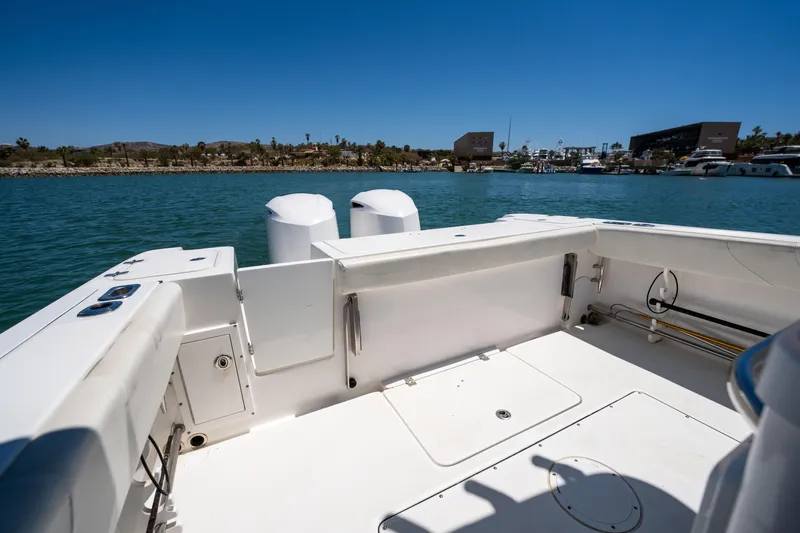 Carnal Yacht Photos Pics Edgewater 320CC 2020 boat deck with dual engines, on calm water under clear blue sky.
