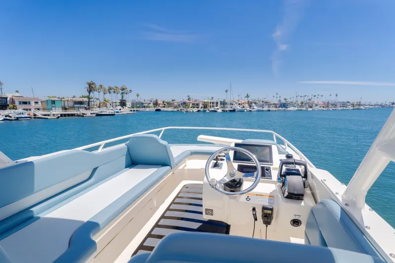 Mandalorian Yacht Photos Pics 2023 Scout 530 LXF boat interior with steering wheel, blue seating, and waterfront view.