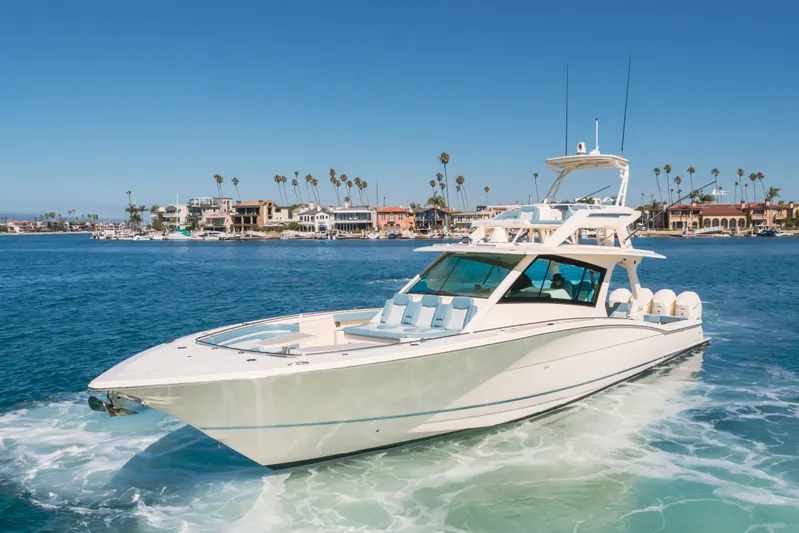 Mandalorian Yacht Photos Pics 2023 Scout 530 LXF luxury yacht cruising near coastal homes under clear blue skies.