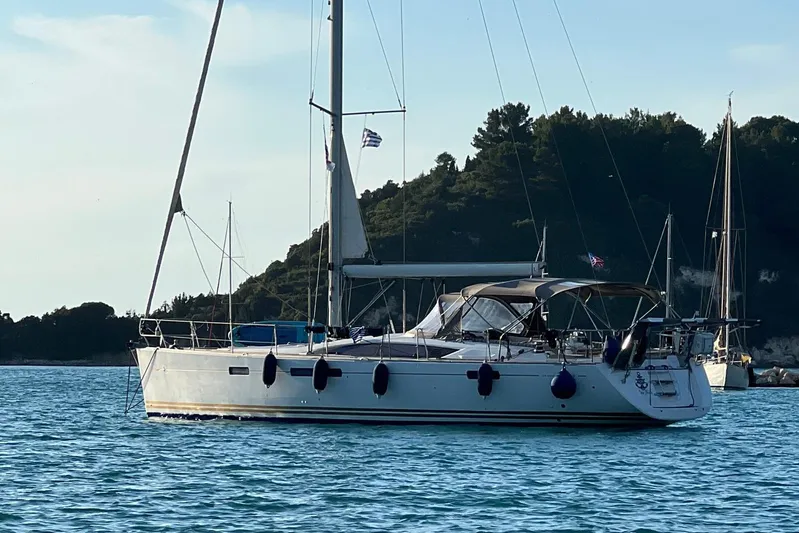  Yacht Photos Pics Sailing yacht Jeanneau 57, 2015 model, anchored in serene waters with scenic backdrop.