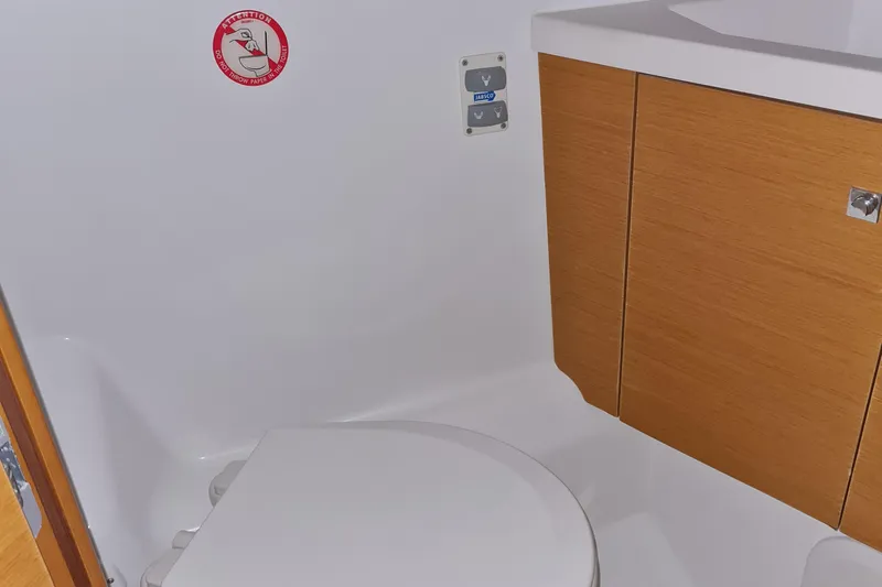  Yacht Photos Pics 2015 Jeanneau 57 yacht bathroom with toilet, wooden cabinet, and caution sign.