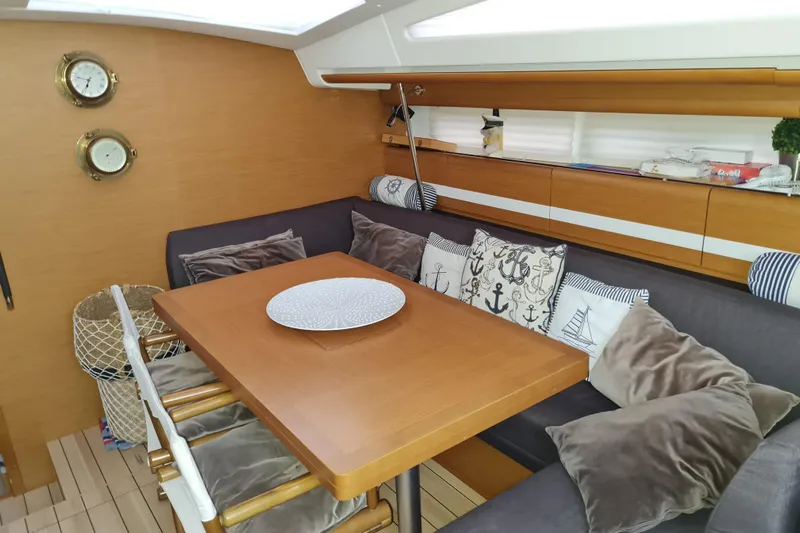  Yacht Photos Pics Cozy interior of 2015 Jeanneau 57 yacht with nautical-themed cushions and wooden dining table.