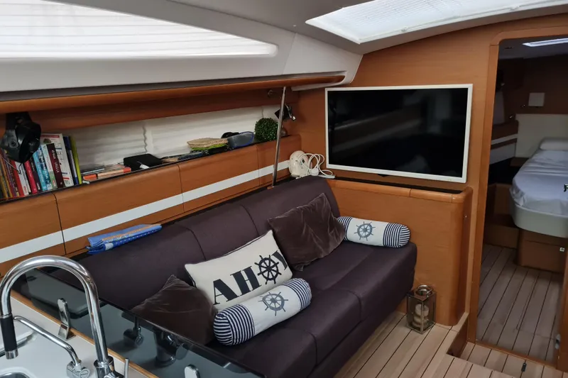  Yacht Photos Pics Interior of 2015 Jeanneau 57 yacht with cozy seating, TV, and nautical decor.
