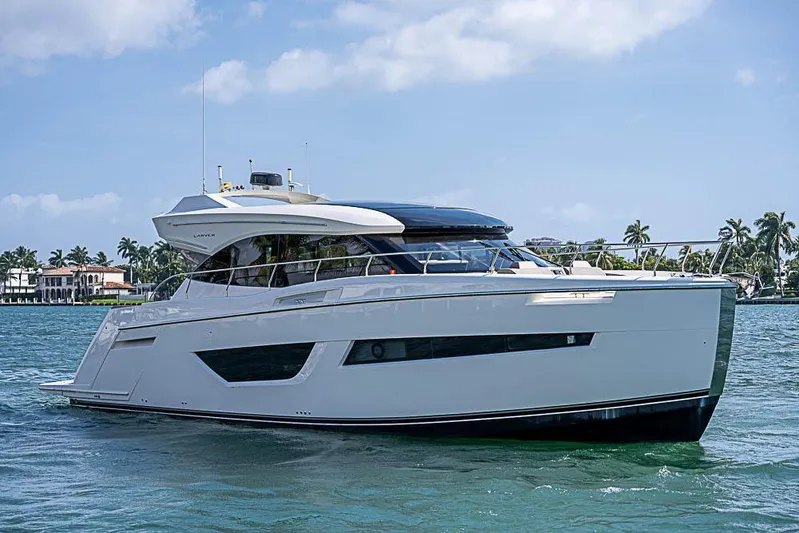  Yacht Photos Pics 2017 Carver C52 Coupe yacht cruising on a sunny day, surrounded by palm trees and waterfront homes.