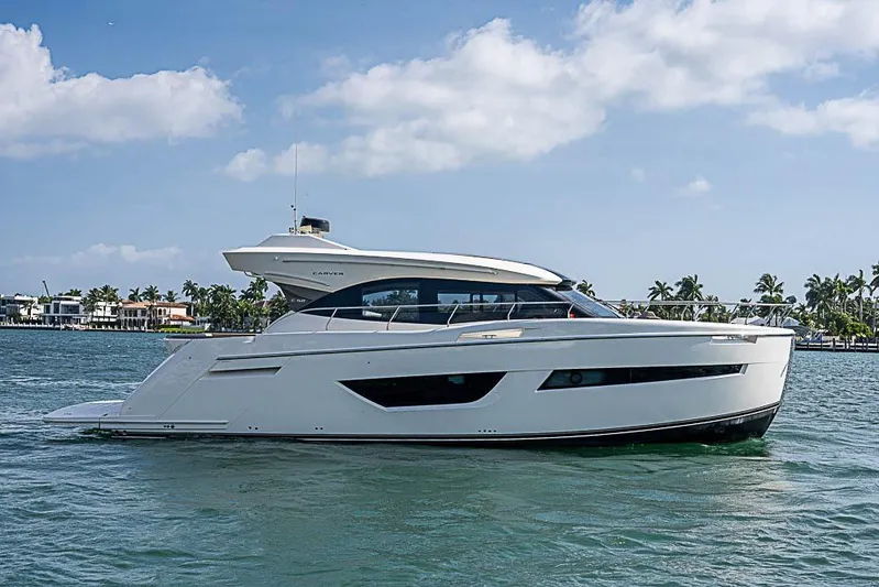  Yacht Photos Pics 2017 Carver C52 Coupe yacht cruising on a sunny day with palm trees in the background.