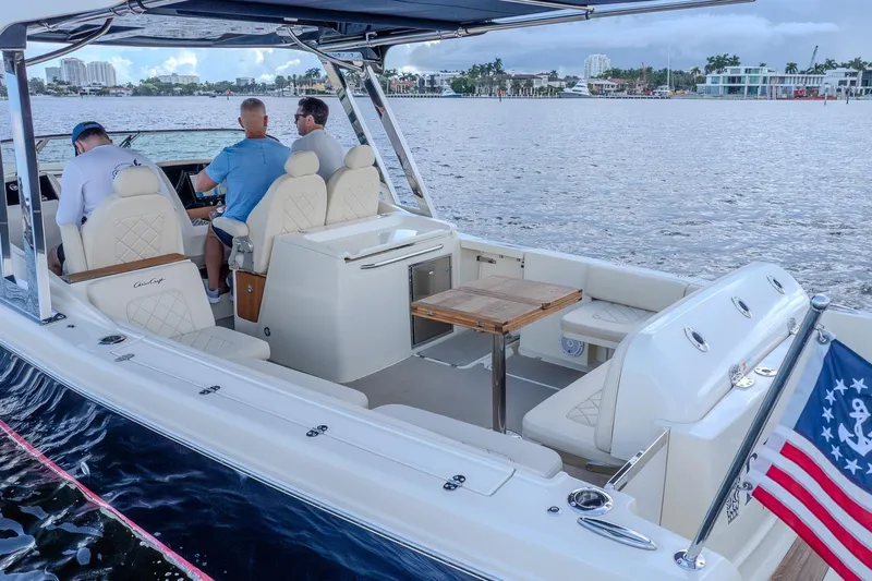 Ritz-sea Yacht Photos Pics 2019 Chris-Craft Calypso 30 boat interior with seating, table, and American flag on water.