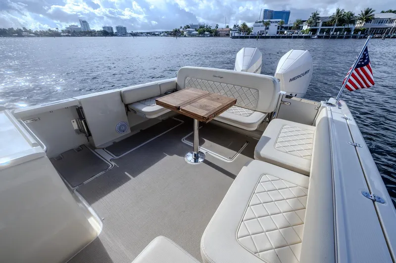 Ritz-sea Yacht Photos Pics 2019 Chris-Craft Calypso 30 boat interior with seating, table, and American flag on a sunny day.