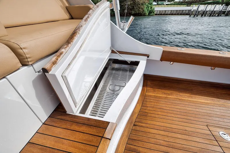 Rainmaker Yacht Photos Pics 2021 Garlington Convertible boat with open storage compartment on teak deck by the water.