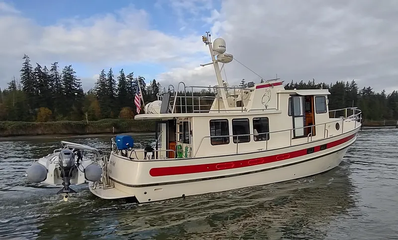 Snowy Owl Yacht Photos Pics 2000 Nordic Tug 42 cruising on a scenic waterway with forested background.