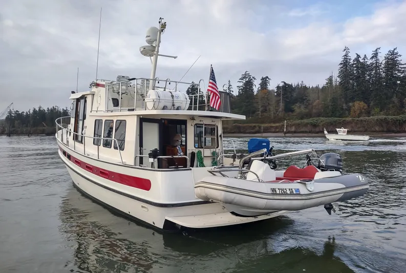 Snowy Owl Yacht Photos Pics 2000 Nordic Tug 42 boat on water with dinghy and American flag.