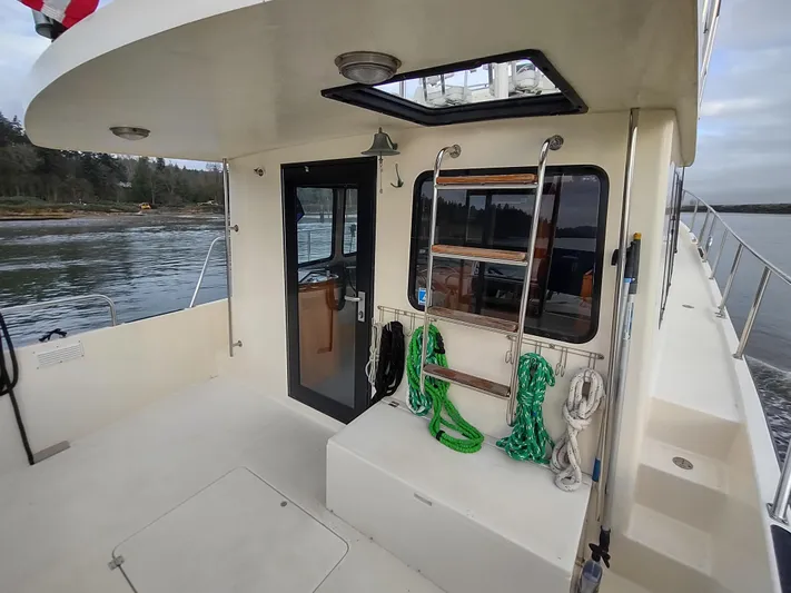 Snowy Owl Yacht Photos Pics 2000 Nordic Tug 42 boat deck with ropes and ladder, docked by the water.