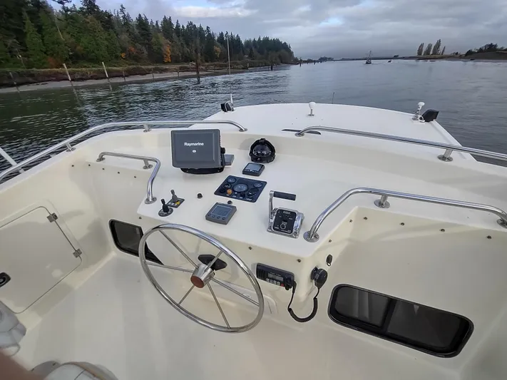 Snowy Owl Yacht Photos Pics Nordic Tug 42 helm with navigation equipment, steering wheel, and scenic waterway view.