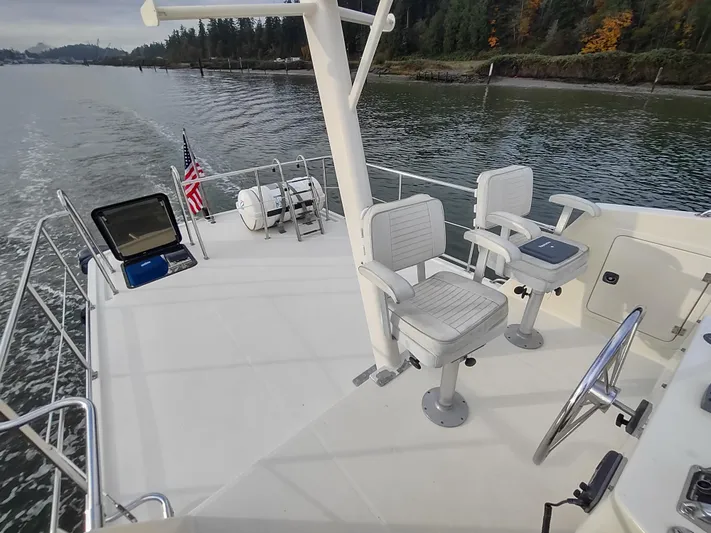 Snowy Owl Yacht Photos Pics Nordic Tug 42 (2000) deck with seating, steering wheel, and scenic waterway view.