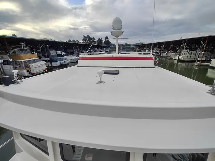 Snowy Owl Yacht Photos Pics Nordic Tug 42 (2000) docked at marina under cloudy sky.