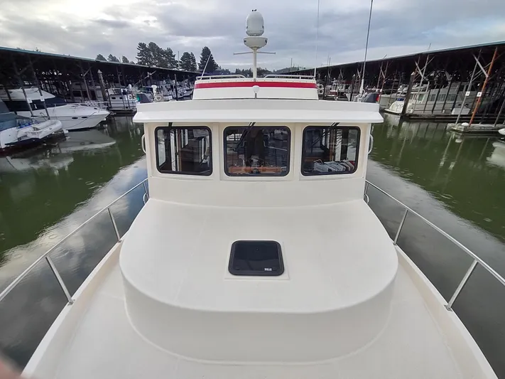 Snowy Owl Yacht Photos Pics 2000 Nordic Tug 42 docked in a marina, showcasing its spacious deck and cabin.