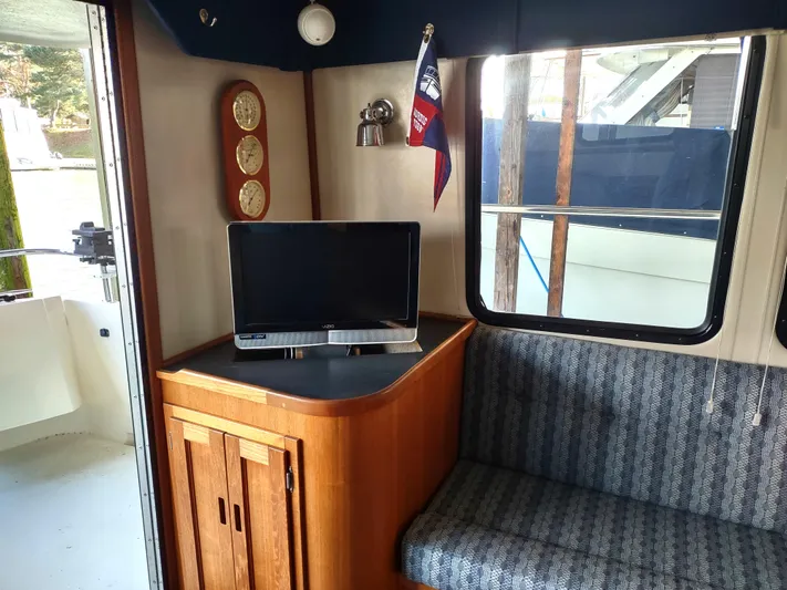 Snowy Owl Yacht Photos Pics Interior of 2000 Nordic Tug 42 with TV, wooden cabinet, and seating area.