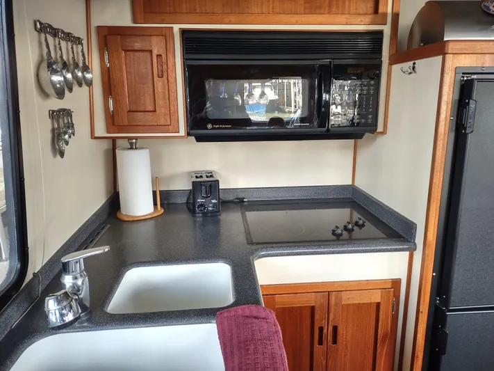 Snowy Owl Yacht Photos Pics Compact kitchen in a 2000 Nordic Tug 42 boat with modern appliances and wooden cabinetry.