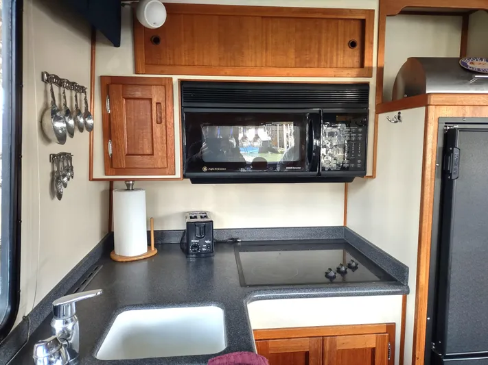 Snowy Owl Yacht Photos Pics Nordic Tug 42 (2000) kitchen with microwave, stove, sink, and wooden cabinets.