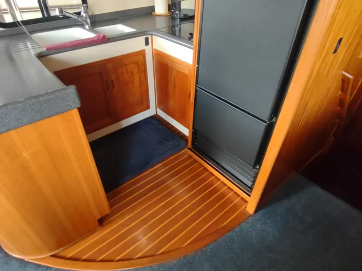 Snowy Owl Yacht Photos Pics Nordic Tug 42 (2000) kitchen area with wood cabinetry and black appliances.