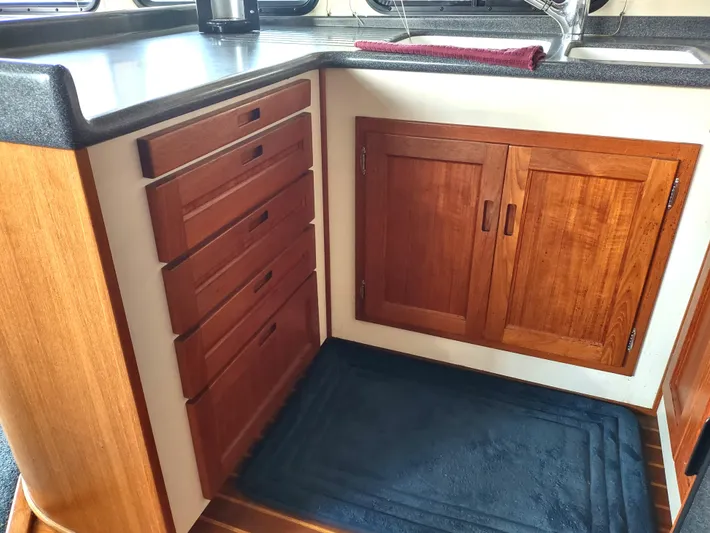 Snowy Owl Yacht Photos Pics Nordic Tug 42 (2000) kitchen with wooden cabinets and drawers, black countertop, and sink.