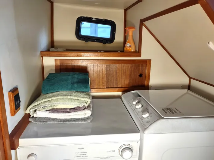 Snowy Owl Yacht Photos Pics Laundry area in 2000 Nordic Tug 42 with washer, towels, and storage shelf.