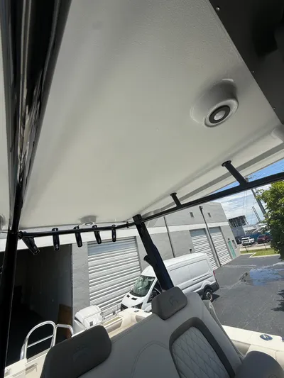  Yacht Photos Pics 2023 World Cat 325 CC boat interior with rod holders and speaker, parked near industrial buildings.