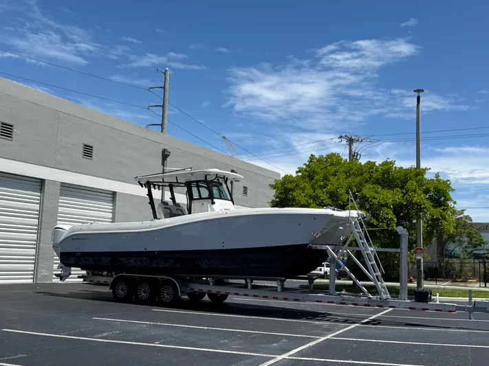  Yacht Photos Pics 2023 World Cat 325 CC boat on trailer in parking lot, clear sky background.
