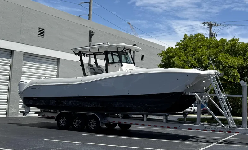  Yacht Photos Pics 2023 World Cat 325 CC boat on trailer, parked near industrial building.