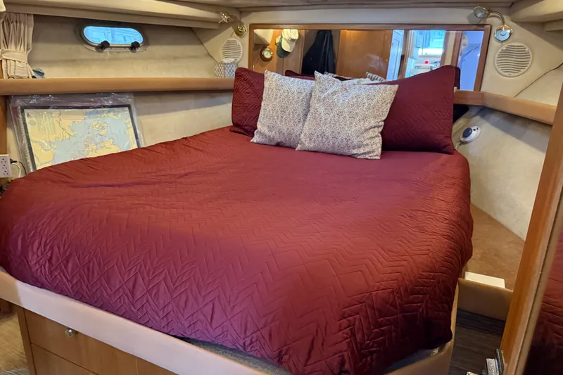  Yacht Photos Pics Cozy bedroom in 1999 Bayliner 3988 Command Bridge Motoryacht with red bedding and nautical decor.