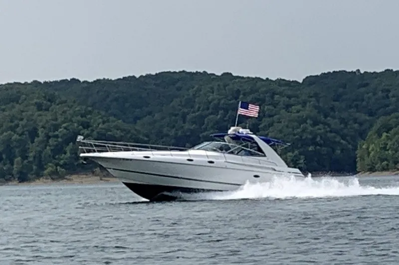  Yacht Photos Pics 2000 Cruisers Yachts 4270 Express cruising on a lake with forested hills in the background.