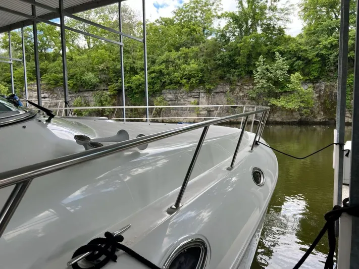  Yacht Photos Pics 2000 Cruisers Yachts 4270 Express docked by a lush, rocky shoreline.