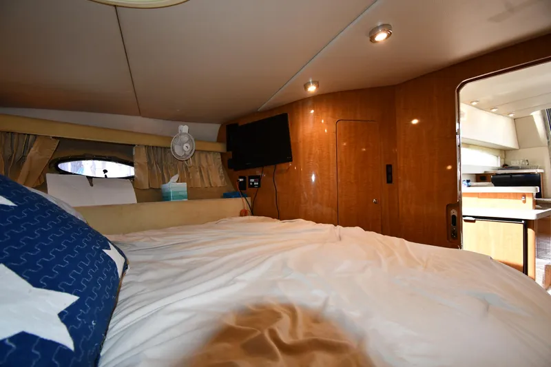  Yacht Photos Pics Cozy bedroom interior of 2003 Regal Commodore 3880 yacht with wood paneling and soft lighting.