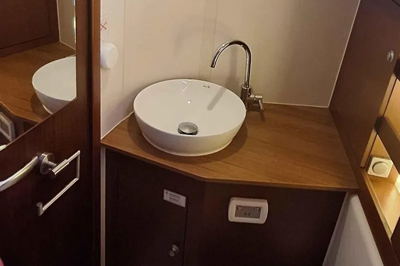  Yacht Photos Pics Compact bathroom sink area in a 2014 Hanse 385 yacht, featuring wooden cabinetry.