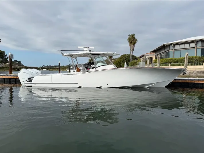  Yacht Photos Pics 2026 Mag Bay 38 CC boat docked by waterfront homes under cloudy sky.