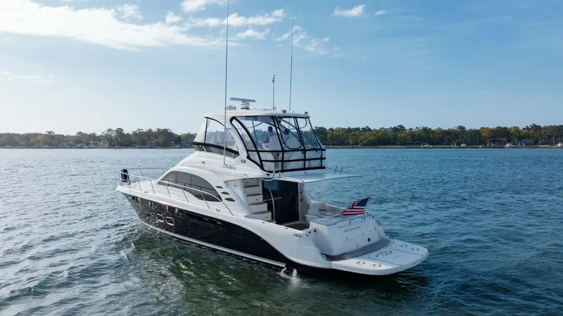Beautiful Blue Yacht Photos Pics 2008 Sea Ray 52 Sedan Bridge yacht cruising on a serene lake under a clear blue sky.