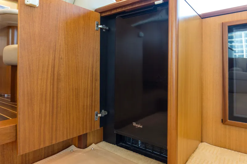 Refuge Yacht Photos Pics Wooden cabinet with open door revealing a Whirlpool appliance on a 2007 Hatteras 68 Enclosed Bridge yacht.