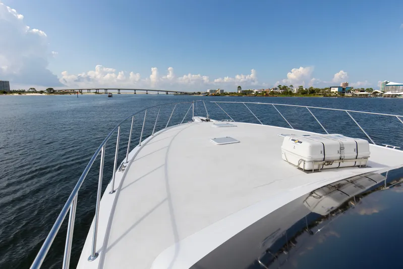 Refuge Yacht Photos Pics Bow view of 2007 Hatteras 68 Enclosed Bridge yacht on calm water near a bridge.