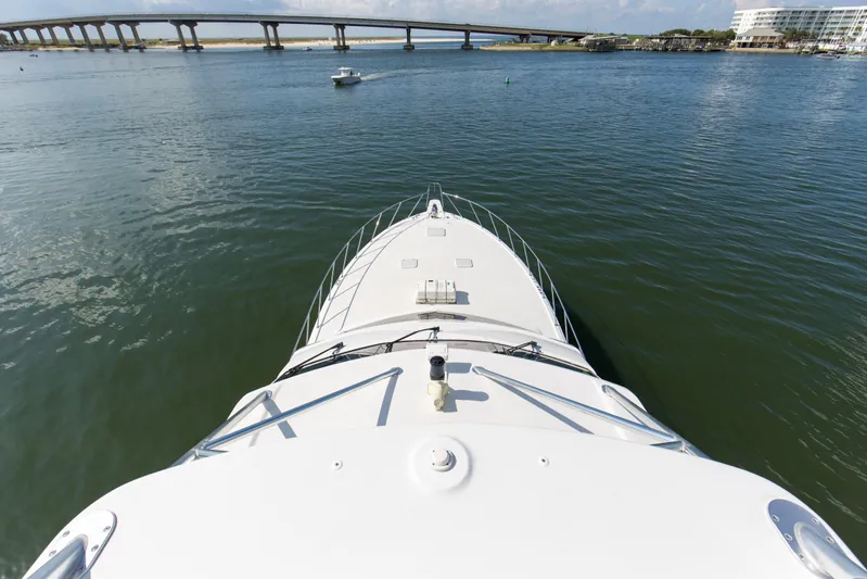 Refuge Yacht Photos Pics Bow view of 2007 Hatteras 68 Enclosed Bridge yacht on calm water near a bridge.
